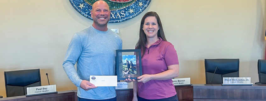 Mayor Bryan McNeal presents a check to Christine New for her photo contest winning photo.