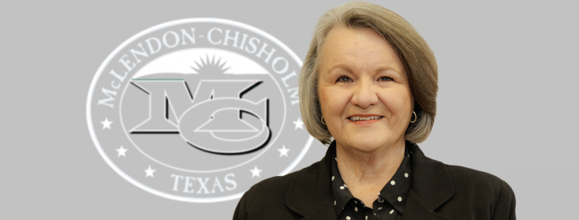 Interim City Administrator Bev Simmons standing in front of a grey background with the McLendon Chisholm logo on the wall.